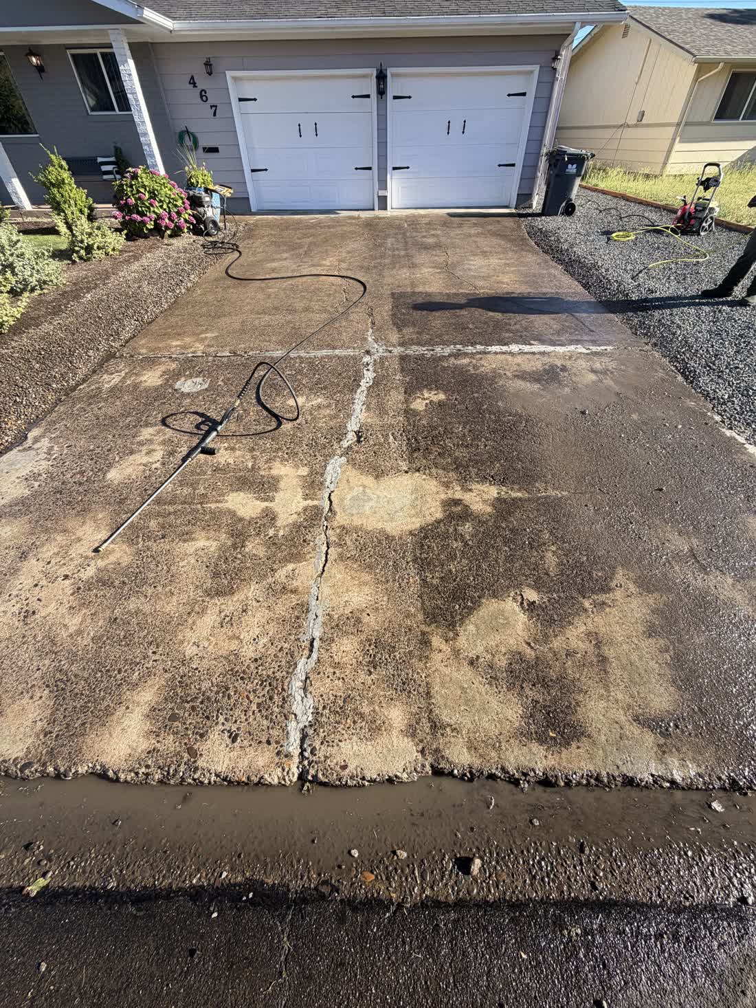 Residential driveway in front of a two-car garage, stained before a pressure wash